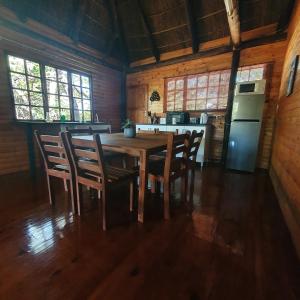 een eetkamer met een tafel en stoelen en een koelkast bij Cozy Wood Cabin in Pretoria