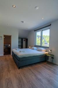 1 dormitorio con cama grande y ventana grande en Vakantiewoning De Bleekersvallei, en De Koog