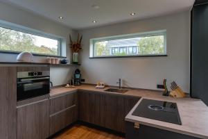 a kitchen with wooden cabinets and a sink and two windows at Vakantiewoning De Bleekersvallei in De Koog