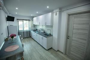 a kitchen with white cabinets and a table and a door at Apartament Serban in Tîrgu Ocna
