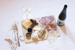 a cutting board with cheese and meats and a bottle of wine at Porta Tosa Boutique in Milan