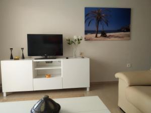 een woonkamer met een wit entertainmentcentrum met een televisie bij Sotavento 1ª línea de playa in Roquetas de Mar