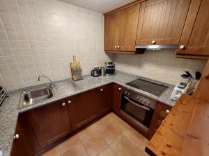 a kitchen with wooden cabinets and a sink and a stove at Family Attic Esterri in Esterri d'Àneu