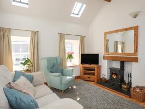 a living room with a couch and a chair and a mirror at Hazel Bank Cottage in Amlwch