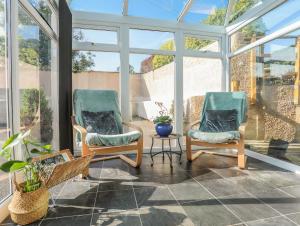two chairs and a table in a room with windows at Hazel Bank Cottage in Amlwch