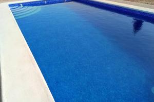 a pool of blue water next to a curb at Villa rústica privada con gran chalet y piscina in Elche