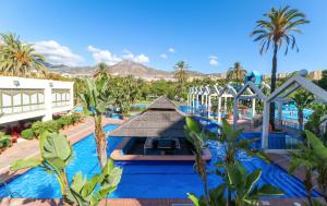 einen Pool in einem Resort mit Palmen und einem Gebäude in der Unterkunft Apartamentos Benal Beach Group in Benalmádena