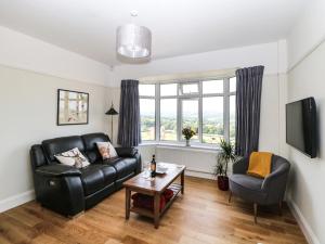 a living room with a black leather couch and a table at The BungalowBarlow in Dronfield