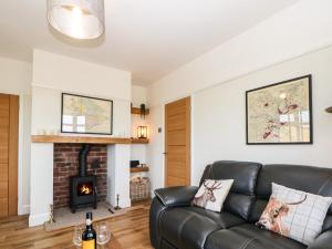 a living room with a black leather couch and a fireplace at The BungalowBarlow in Dronfield