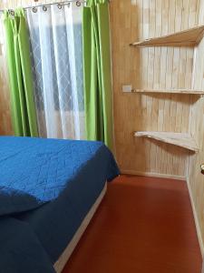 1 dormitorio con 1 cama y cortinas y estanterías verdes en Cabañas Genesis, en Choshuenco