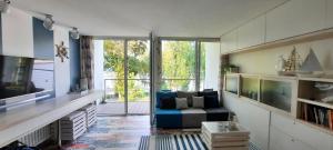 a living room with a couch and a large window at Apartament Lazurowy 53 z tarasem i SPA in Gródek Nad Dunajcem