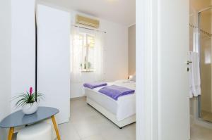 Un dormitorio blanco con una cama y una mesa. en Rooms Batina, en Dubrovnik