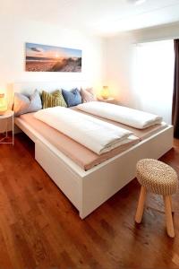 uma grande cama branca num quarto com uma cadeira em Bright and modern apartment in the heart of Altstätten em Altstätten