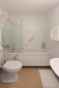 a bathroom with a toilet and a tub and a sink at Bright and modern apartment in the heart of Altstätten in Altstätten