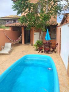 uma grande piscina azul em frente a uma casa em Casa com piscina e churrasqueira em Iguaba Grande