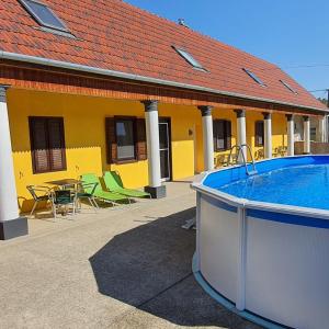 un edificio amarillo con piscina, mesa y sillas en Panzio A mi Paradicsomunk, en Véménd