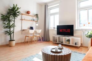 ein Wohnzimmer mit einem TV und einem Tisch in der Unterkunft Stilvolles Apartment mit Balkon / Netflix + WIFI & zentrumsnah in Chemnitz