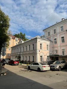 eine Gruppe von Autos, die vor einem Gebäude geparkt sind in der Unterkunft Mila Guest House in Moskau