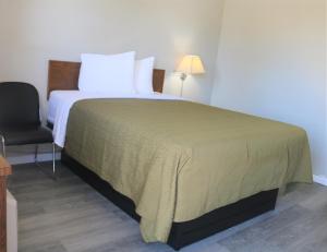 a bedroom with a large bed and a chair at Ranch Motel in Salem