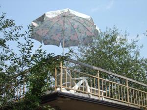 uma pessoa de pé numa varanda com um guarda-chuva em Rooms and Suites Ljetnikovac em Daruvar