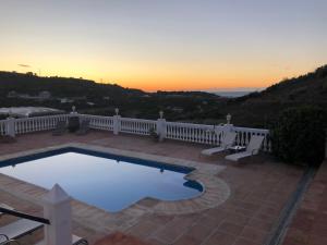 una piscina en un patio con una puesta de sol en el fondo en Villa Sunshine Countryside Resort en Frigiliana