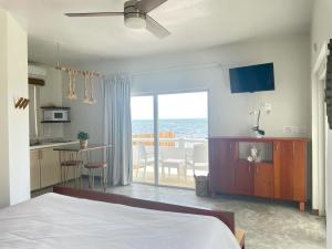 a bedroom with a bed and a kitchen with a view of the ocean at Mata Rocks Resort in San Pedro
