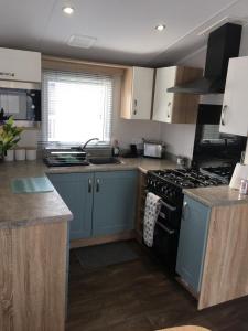 a kitchen with blue cabinets and a stove top oven at 6 Swan View Haven, Littlesea in Weymouth