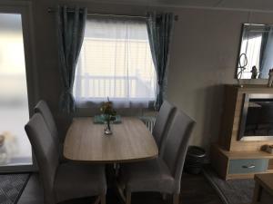 a dining room table with chairs and a window at 6 Swan View Haven, Littlesea in Weymouth