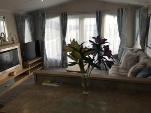 a living room with a couch and a vase of flowers at Swan View Haven, Littlesea in Weymouth