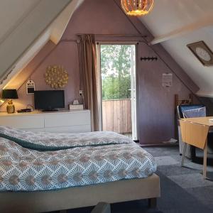 a bedroom with a bed and a table and a window at Logeren op Dijk43 in Broek op Langedijk