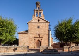 an old brick building with a tower with a cross at Casa de la Gloria in Baños de la Encina