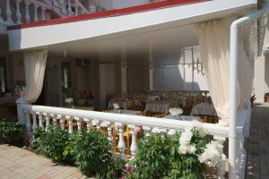 a restaurant with a balcony with tables and curtains at Privat Pansionat Semeynyy in Nikolaevka