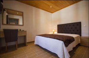 a bedroom with a bed and a desk and a mirror at Casa De Campo Cantinho Da Serra in Cortelha