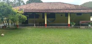 a yellow house with a red roof in a yard at Casa do Maurição Refúgio da Família in Casimiro de Abreu