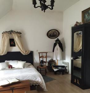 een slaapkamer met een bed, een spiegel en een stoel bij La Romanée in Sallaumines