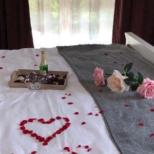 un letto con una bottiglia di champagne e un cuore di rose di Pensiunea Pont-Euxin a Constanţa