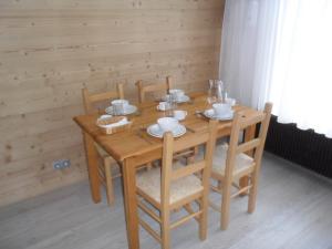 una mesa de madera con sillas, platos y tazas. en Studio les 2 Aples, en Les Deux Alpes