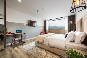 a hotel room with a bed and a desk and a window at Go Living and Suites El Poblado - Jalo Rent in Medellín