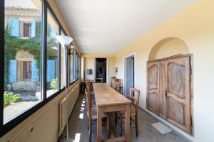 a dining room with a table and some windows at MAISON AVEC PISCINE - PROCHE AVIGNON - WiFI GRATUIT in Sauveterre
