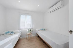 biały pokój z 2 łóżkami i oknem w obiekcie Apartamento tranquilo a 500m de la playa w mieście Punta Grossa