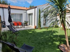 un patio trasero con una palmera y una casa en Le clos des baigneurs en Dolus d'Oléron