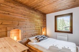 - une chambre dotée d'un mur en bois avec un lit et une table dans l'établissement Appartement des Cerisiers - Welkeys, à Megève
