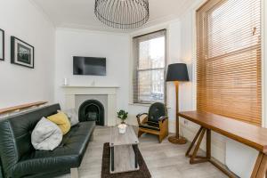 a living room with a black leather couch and a fireplace at Radio Apartments London - Covent Garden in London