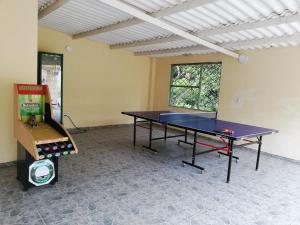 a ping pong table in a room with a video game at Hacienda el Paraiso Villeta in Villeta