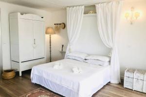 een witte slaapkamer met een wit bed en witte handdoeken. bij Casa Acacia in Fiorenzuola di Focara