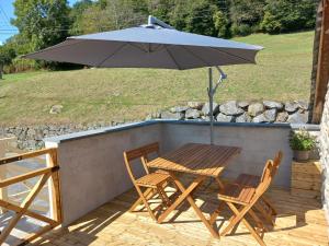 a wooden table and chairs with an umbrella on a patio at Logement entièrement rénové au cœur du Val d'Azun in Arras-en-Lavedan +2 photos