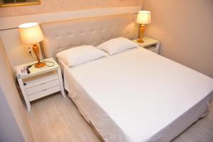 um quarto com uma cama branca e 2 candeeiros nas mesas em Ecos Hotel Tourist em Rolim de Moura