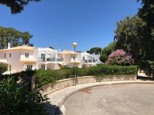 une grande maison blanche avec une clôture en pierre et des fleurs dans l'établissement Algarve Albufeira, quiet apart with pool at 10 mn walk from Praia da Falesia, à Olhos de Água