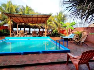 a swimming pool with a gazebo and a table and chairs at El Belga Loco in Las Peñitas