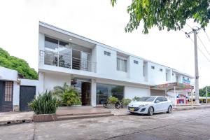 a white building with a car parked in front of it at Hotel Millrose in Valledupar